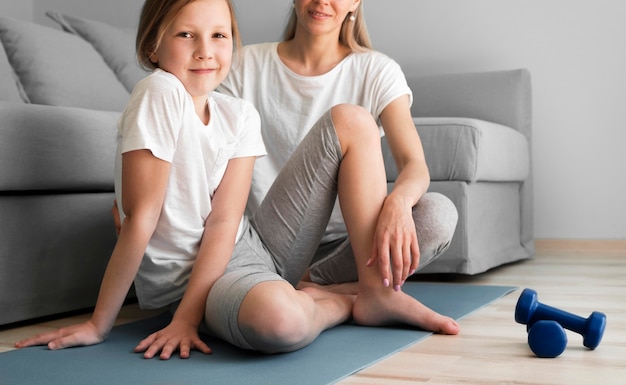 Foto gratuita madre y niña entrenando con pesas en colchoneta