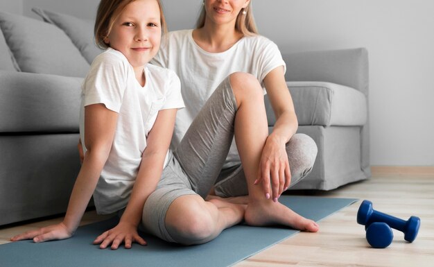 Madre y niña entrenando con pesas en colchoneta