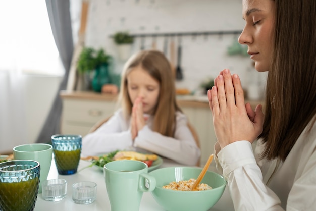 Madre y niña rezando en la mesa