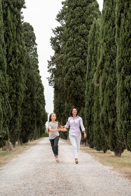 Madre y niña de tiro largo caminando juntas