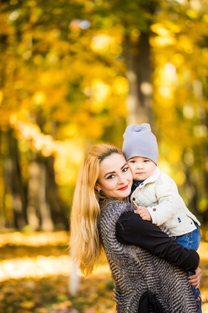 La madre y el niño caminan en el parque de otoño dorado.