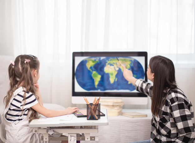 Una madre con un niño se sienta a la mesa y hace la tarea.