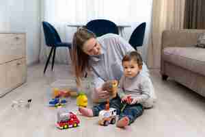 Foto gratuita madre y niño sonrientes de tiro completo en casa