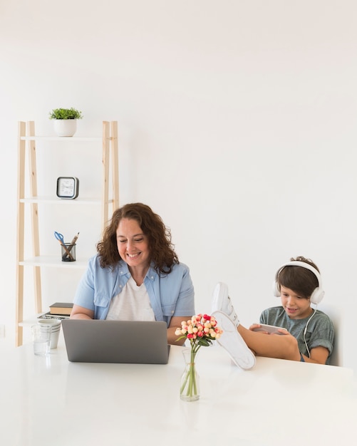 Madre con niño trabajando en la computadora portátil