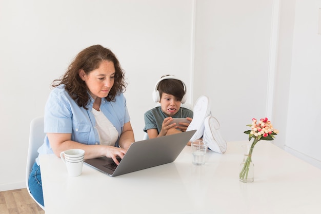 Madre con niño trabajando en la computadora portátil