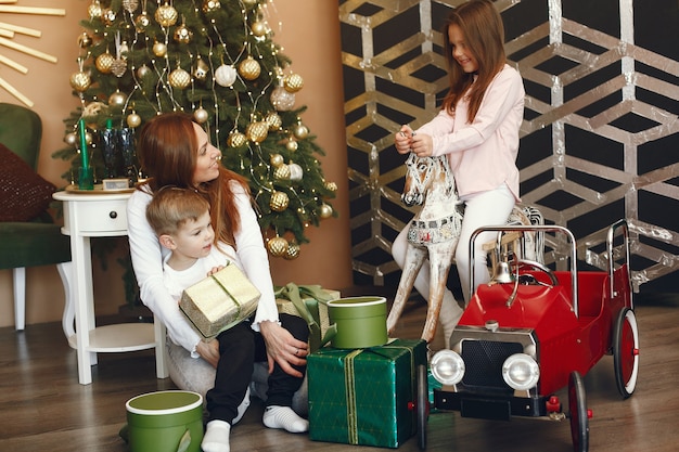 Madre con niños lindos cerca del árbol de Navidad