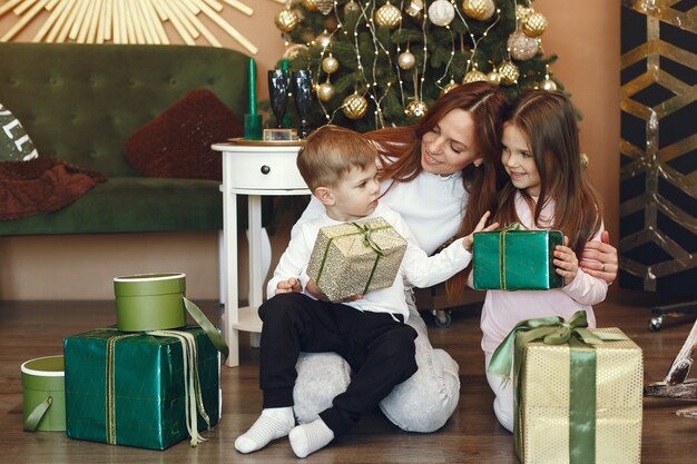 Madre con niños lindos cerca del árbol de Navidad