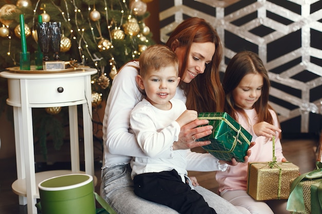 Madre con niños lindos cerca del árbol de Navidad