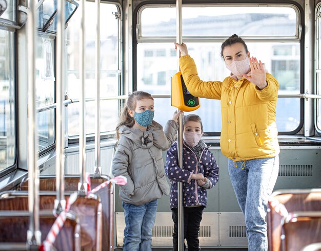 Una madre con niños pequeños con máscaras se protege del coronavirus en el transporte público.