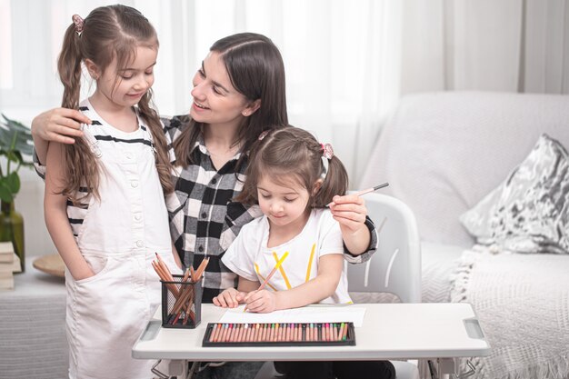 Madre con niños sentados a la mesa y hacer la tarea.