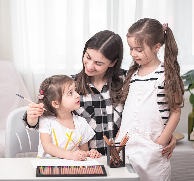 Madre con niños sentados a la mesa y haciendo los deberes. El niño aprende en casa. Educación en casa. Espacio para texto.