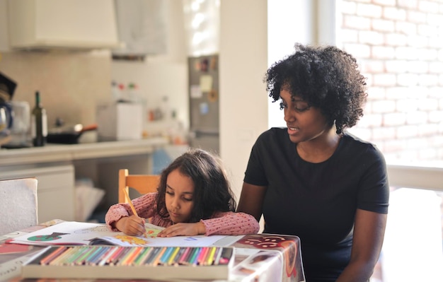 madre observa a su hija coloreando un cuaderno en casa