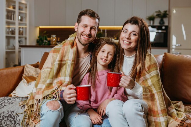 Madre y padre con bebidas calientes con mi hija en casa