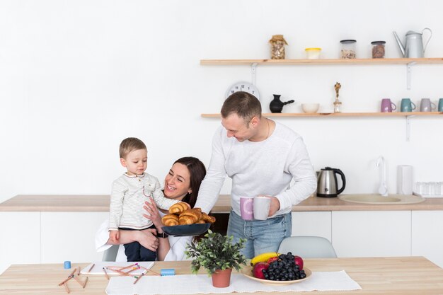 Madre y padre en la cocina con niño y espacio de copia