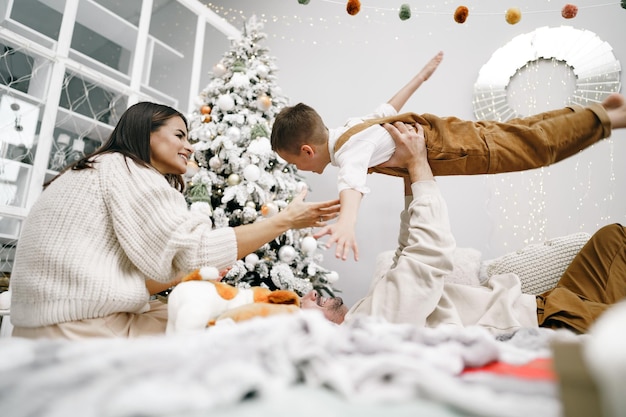 Madre, padre e hijo se divierten en la cama el día de Navidad