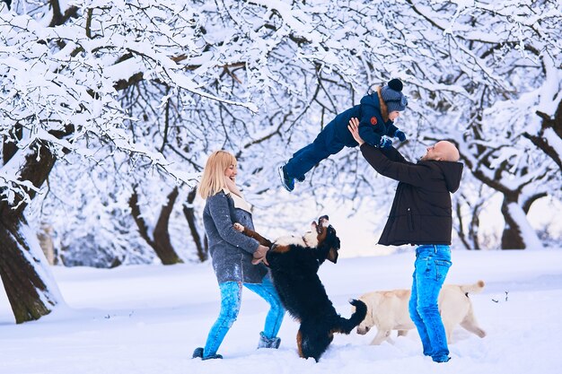 La madre, el padre y el hijo jugando con perros