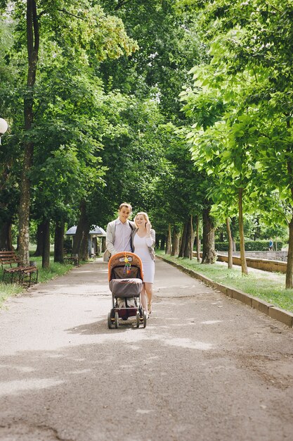 Madre y padre joven paseando a su bebé por el parque