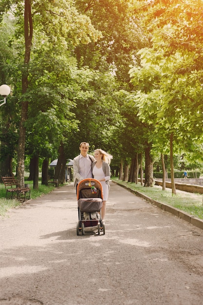 Madre y padre joven paseando a su bebé por el parque