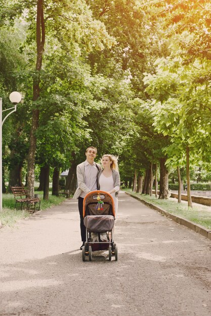 Madre y padre joven paseando a su bebé por el parque