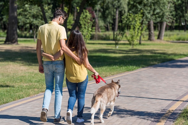 Madre y padre en el parque paseando al perro.