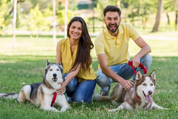 Madre y padre posando con sus perros en el parque.