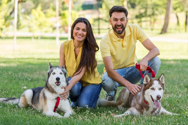 Madre y padre posando con sus perros en el parque.