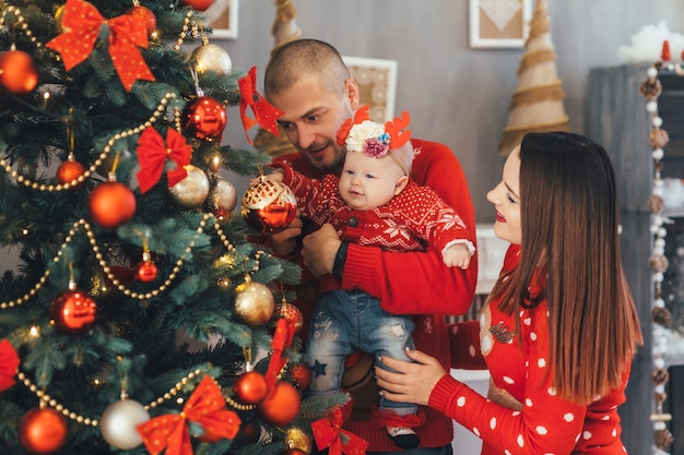 La madre y el padre tienen en las manos a su hija