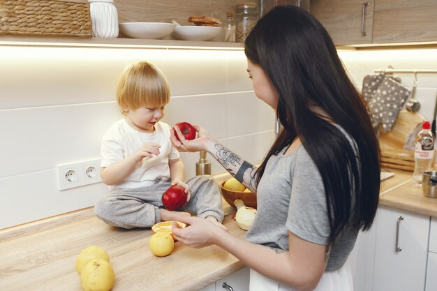 Madre con pequeño hijo comiendo frutas en una cocina