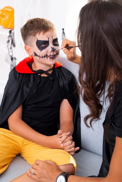 Madre pintando la cara de sus hijos para halloween