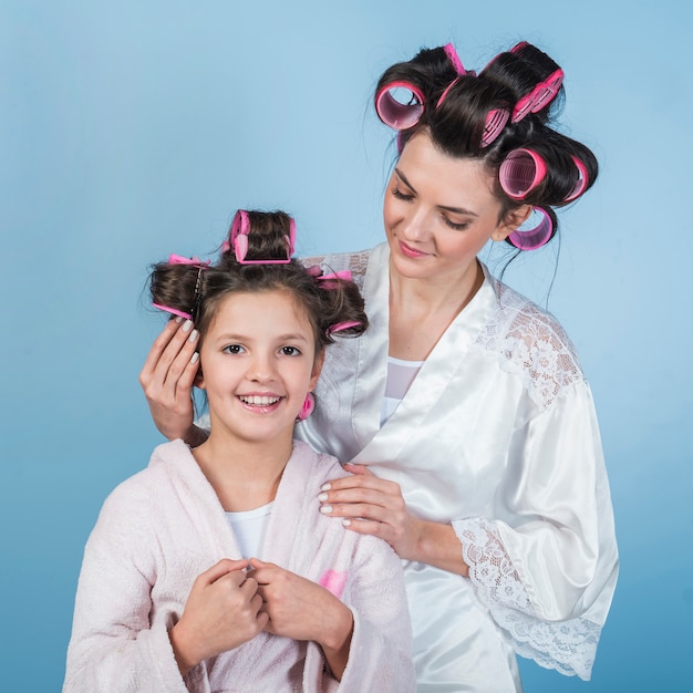 Madre poniendo rizador en el pelo de hijas