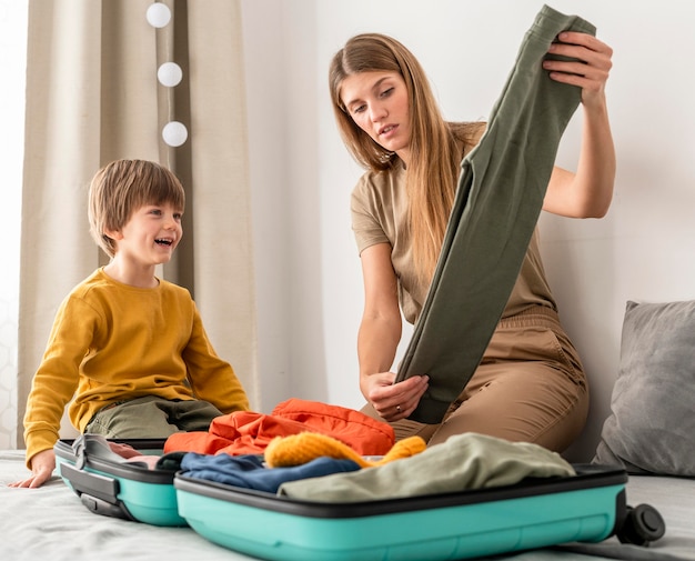 Foto gratuita madre preparando equipaje de viaje con hijo