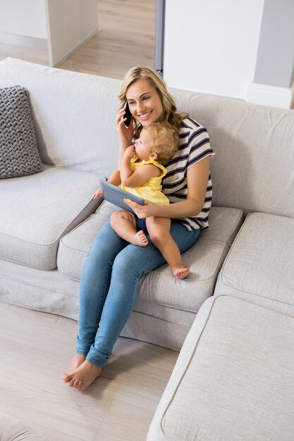 Madre que habla en el teléfono móvil mientras sostiene a su bebé