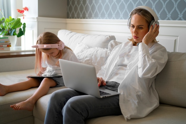 Foto gratuita madre que trabaja desde casa tratando de equilibrar la vida familiar con el niño y el trabajo