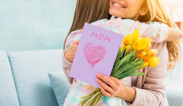 Madre con regalos abrazando a hija y sonriendo