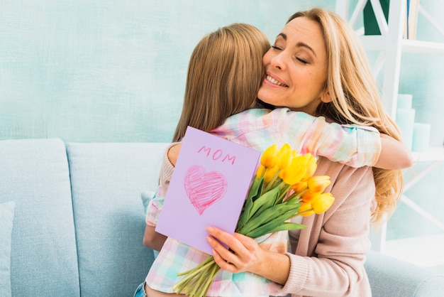 Madre con regalos abrazando hija