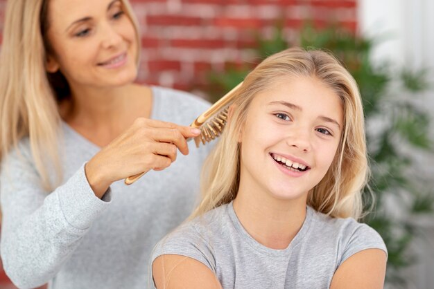 Madre rubia peinando el cabello de su hija