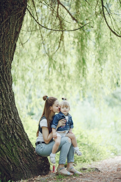 Madre sentada en un árbol con su hija sentada en sus piernas