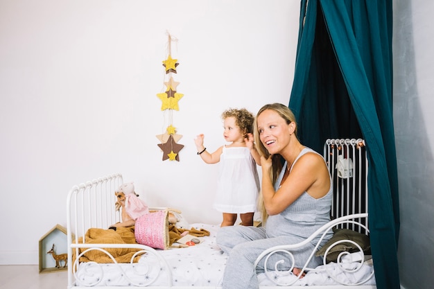 Madre sentada en la cama cerca de bebé