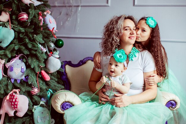 &quot;Madre sentada con hijas sonriendo abrazos&quot;