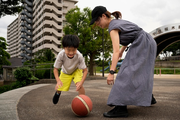 Foto gratuita madre soltera jugando baloncesto con su hijo