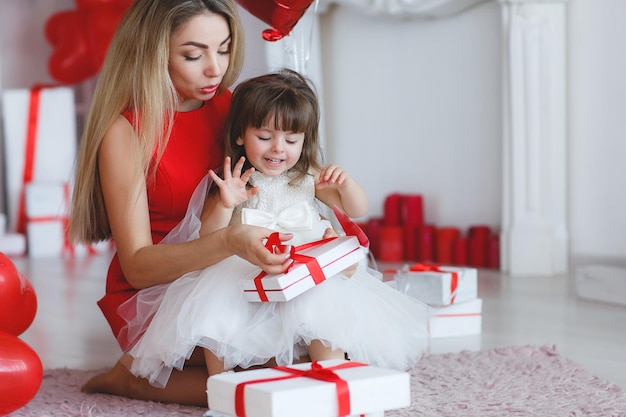 madre sonriente jugando y abriendo regalo con su hijo en casa