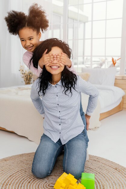 Madre sonriente jugando en casa con su hija