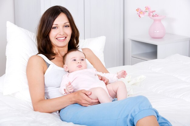 Madre sonriente sentada con el bebé en casa