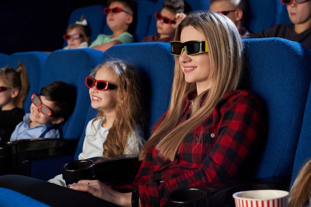 Madre sonriente sentada con pequeña hija en cine