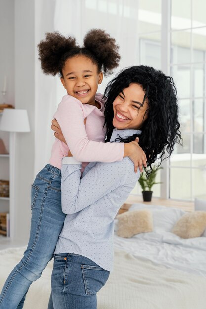 Madre sonriente sosteniendo a su pequeña hija