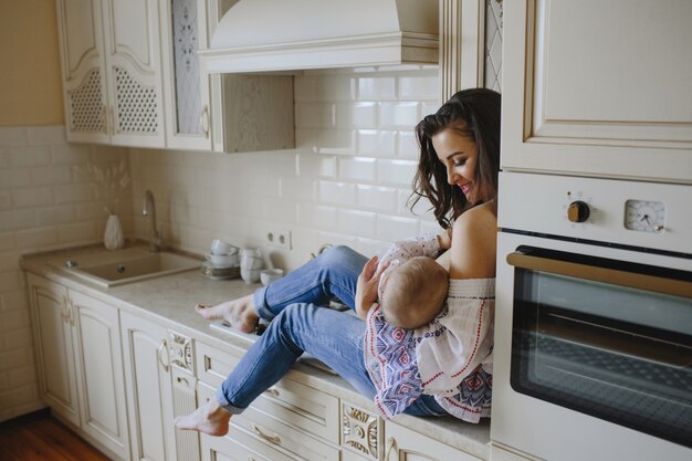 una madre sonriente sostiene al bebé en su cocina