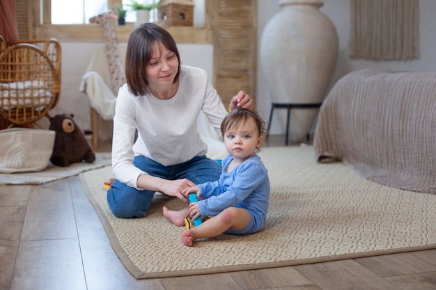 Foto gratuita madre sonriente de tiro completo con bebé en casa