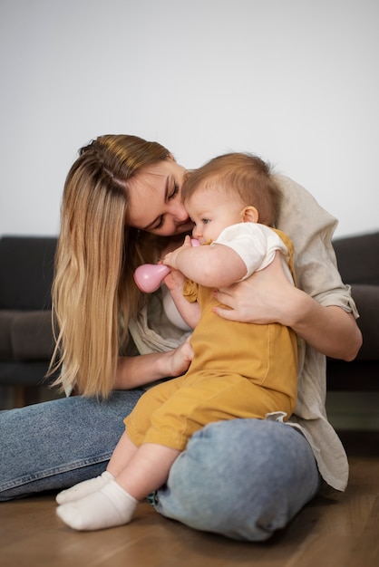 Foto gratuita madre sonriente de tiro completo con bebé