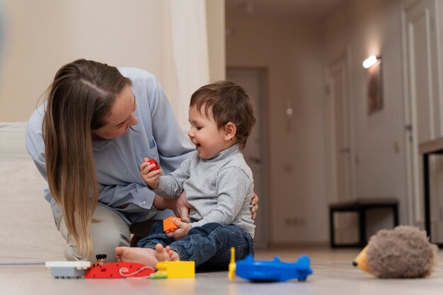 Madre sonriente de tiro completo y niño jugando juntos