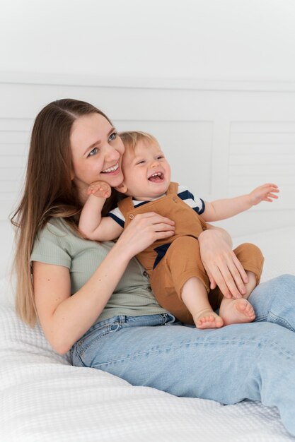 Madre sonriente de tiro medio con niño pequeño